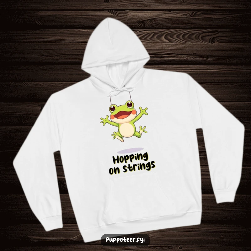 Funny hoodie featuring a cheerful frog character leaping, manipulating a frog puppet with strings for a dynamic, fun effect.