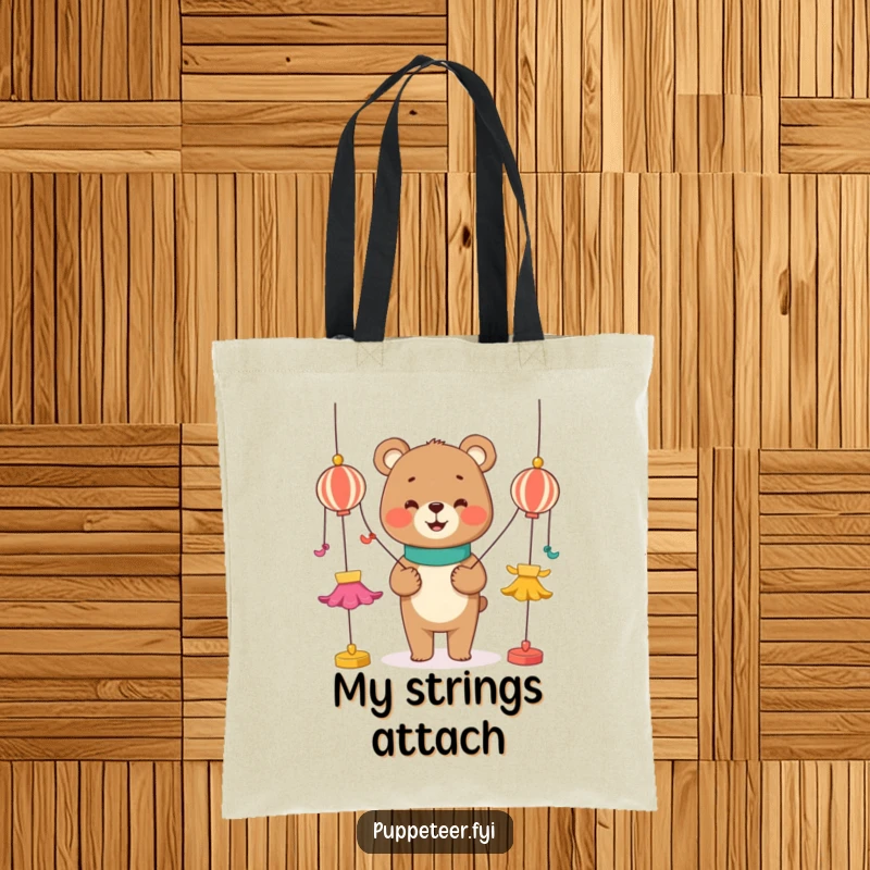 Funny tote bag depicting a smiling bear character manipulating colorful strings attached to dancing puppets, a unique and humorous accessory.